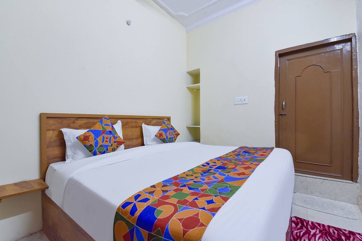 A bed with a colorful geometric-patterned bedspread, a wooden headboard, and white bedding.