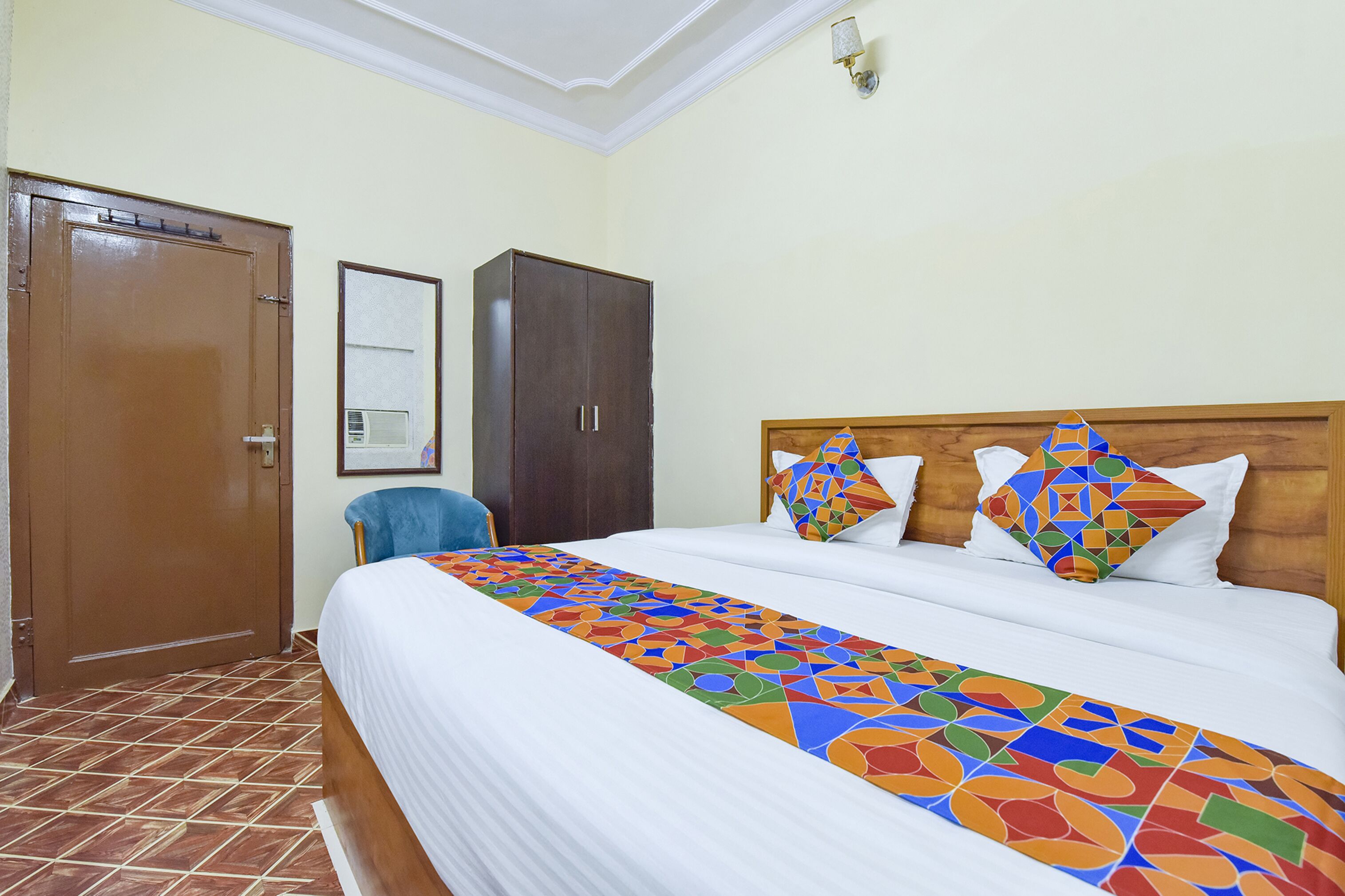 A hotel room with a bed, a wardrobe, and a chair.