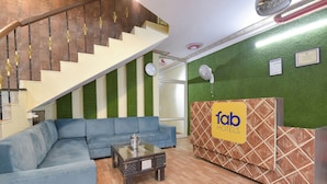 A lobby with a blue sofa, a reception desk, a staircase, and a clock on the wall. - Fabhotel Rajwada Palace (Jaipur)