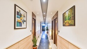 A hotel hallway with wooden paneling, a tiled floor, and artwork on the walls. - Fabhotel Shaurya Inn (Lucknow)
