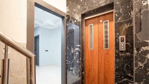 An elevator with a wooden door and marble walls. - FabHotel The Royal - Near Yamuna Sports Complex (New Delhi)