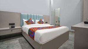 A modern hotel room with a large bed, a bedside table, a nightstand, a mirror, and a small desk with a chair. - FabHotel The Royal - Near Yamuna Sports Complex (New Delhi)