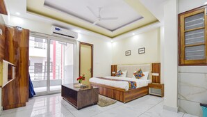 A modern bedroom with a bed, bedside tables, a wooden wardrobe, and a ceiling fan. - Fabhotel Hari Om Inn (Rishikesh)