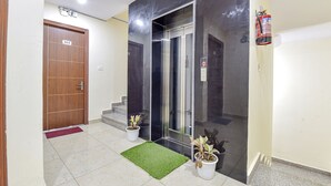 A modern elevator with a digital display, a wooden door labeled "303", and a fire extinguisher on the wall. - Fabhotel Hari Om Inn (Rishikesh)