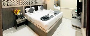 A neatly arranged hotel room with a large bed, a bedside table with a vase of flowers, a mirror, and a television. - Fabhotel Sprinkle Stay (Hyderabad)
