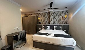 A bedroom with a bed, a desk, a wardrobe, and a ceiling fan. - Fabhotel Sprinkle Stay (Hyderabad)