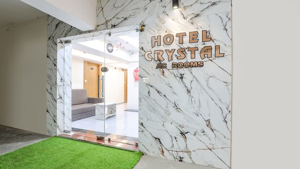 A hotel entrance with marble walls and a green artificial grass area. - Fabhotel Crystal I (Gandhinagar)