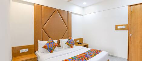 Camera d'albergo moderna con un letto grande, una testiera in legno, comodini e una ventola a soffitto.