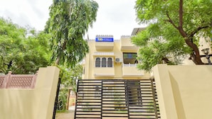 A hotel entrance with a gated entrance, a signboard, and a building with balconies. - Fabhotel Prism Homestay (Jaipur)