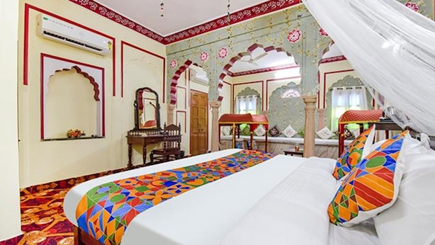 A room with a bed, a mirror, a wooden dresser, and a decorative canopy. - Fabhotel Prism Homestay (Jaipur)
