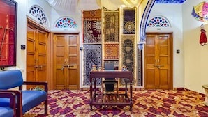 A room with wooden doors, a patterned carpet, and a small table with chairs. - Fabhotel Prism Homestay (Jaipur)