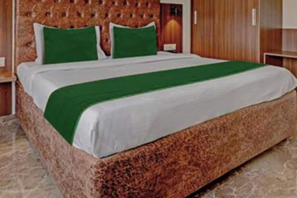 A large bed with a tufted headboard, green pillows, and a green bedspread.