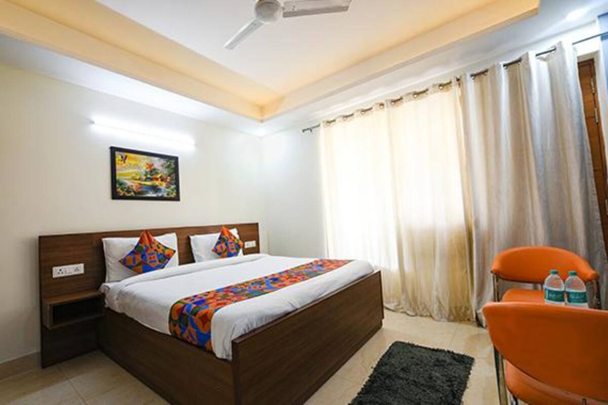 A hotel room with a bed, a nightstand, a chair, and a ceiling fan.