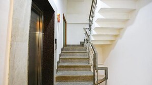 Un escalier avec des rampes en métal et des marches en pierre menant à un ascenseur.