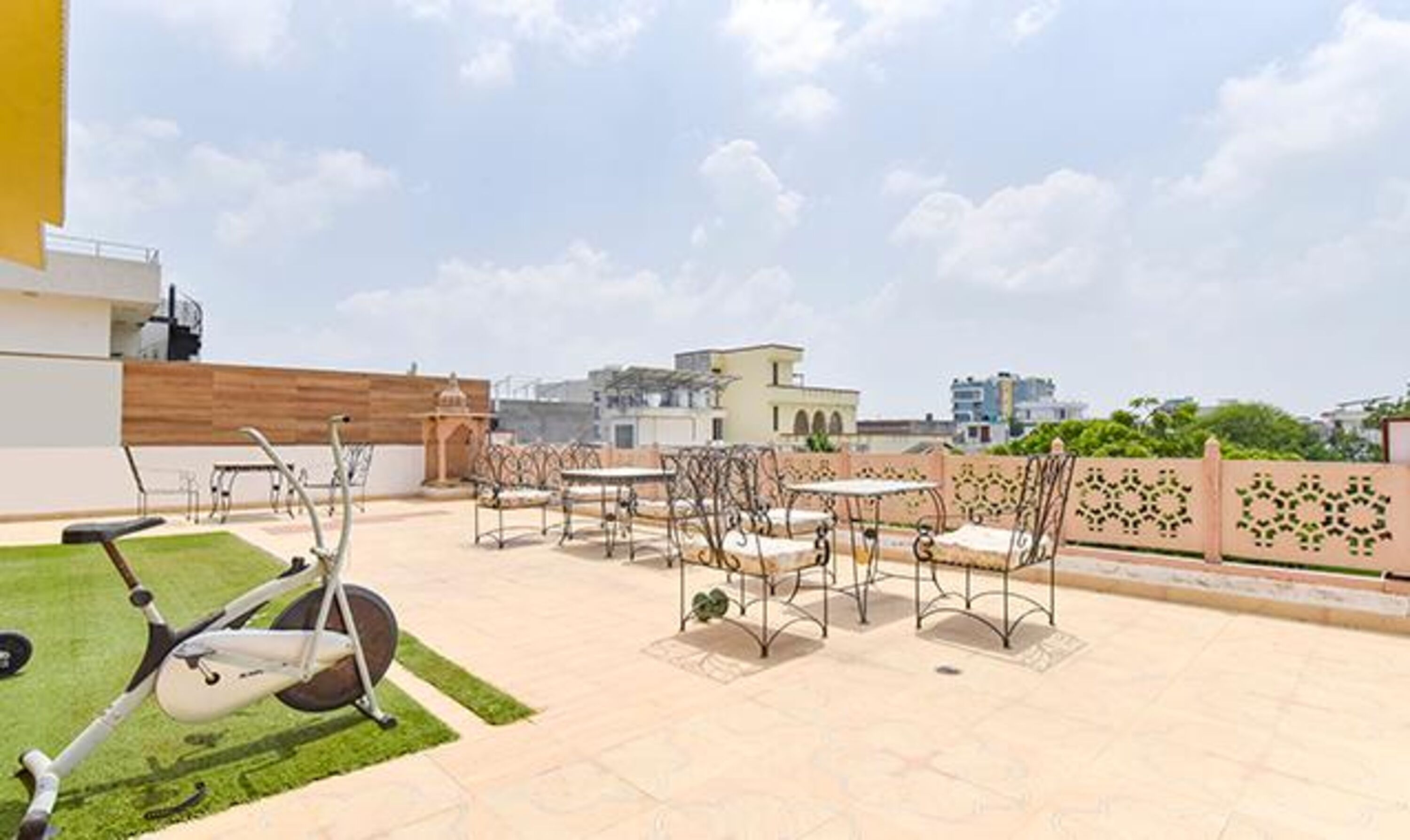 Une terrasse sur le toit équipée d’appareils de musculation, d’un espace de détente extérieur et offrant une vue sur les bâtiments environnants.
