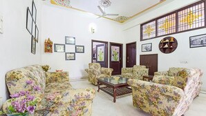 Una sala de estar con sofás de estampado floral, una mesa de centro de vidrio y un ventilador de techo.
