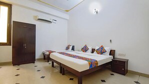 Una habitación de hotel con una cama grande, un armario, una mesita de noche y aire acondicionado instalado en la pared.