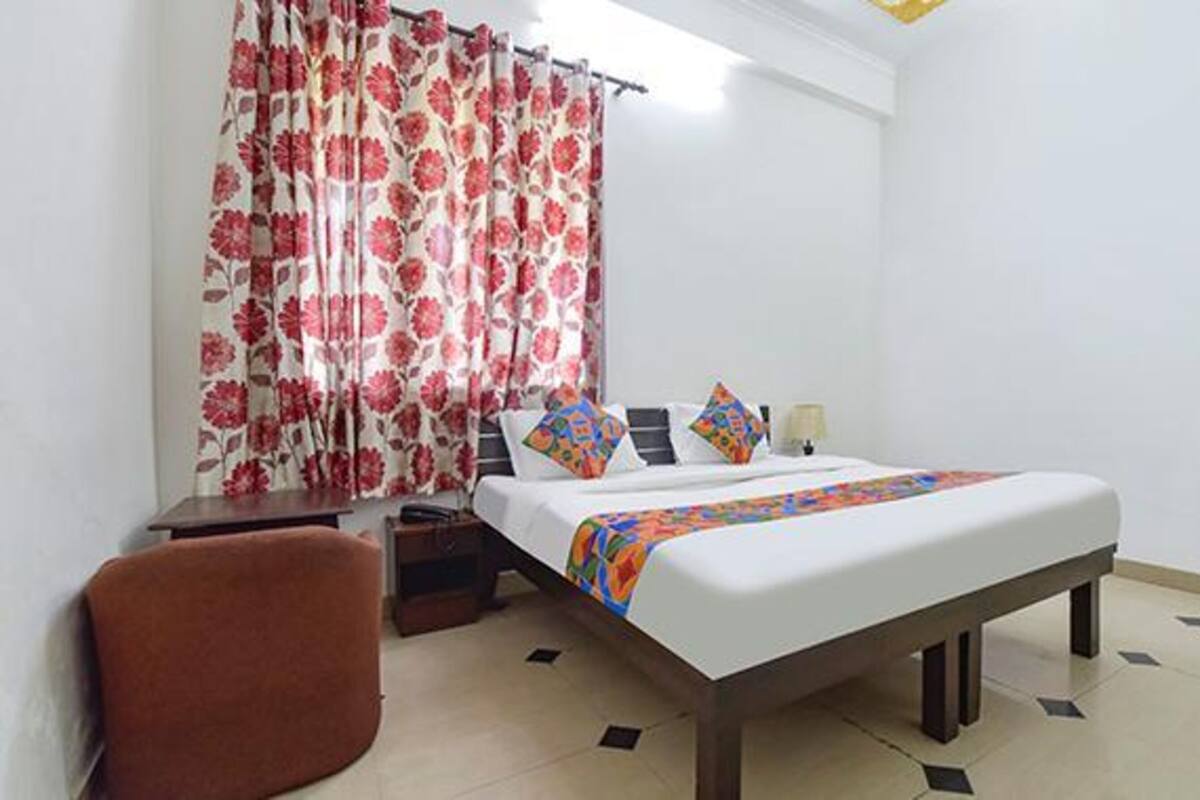 A bedroom with a bed, a desk, a chair, and a curtain with a floral pattern.