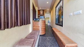 A hotel reception area with a reception desk, a bench, and a reception sign. - Fabhotel Lali Palace (Udaipur)