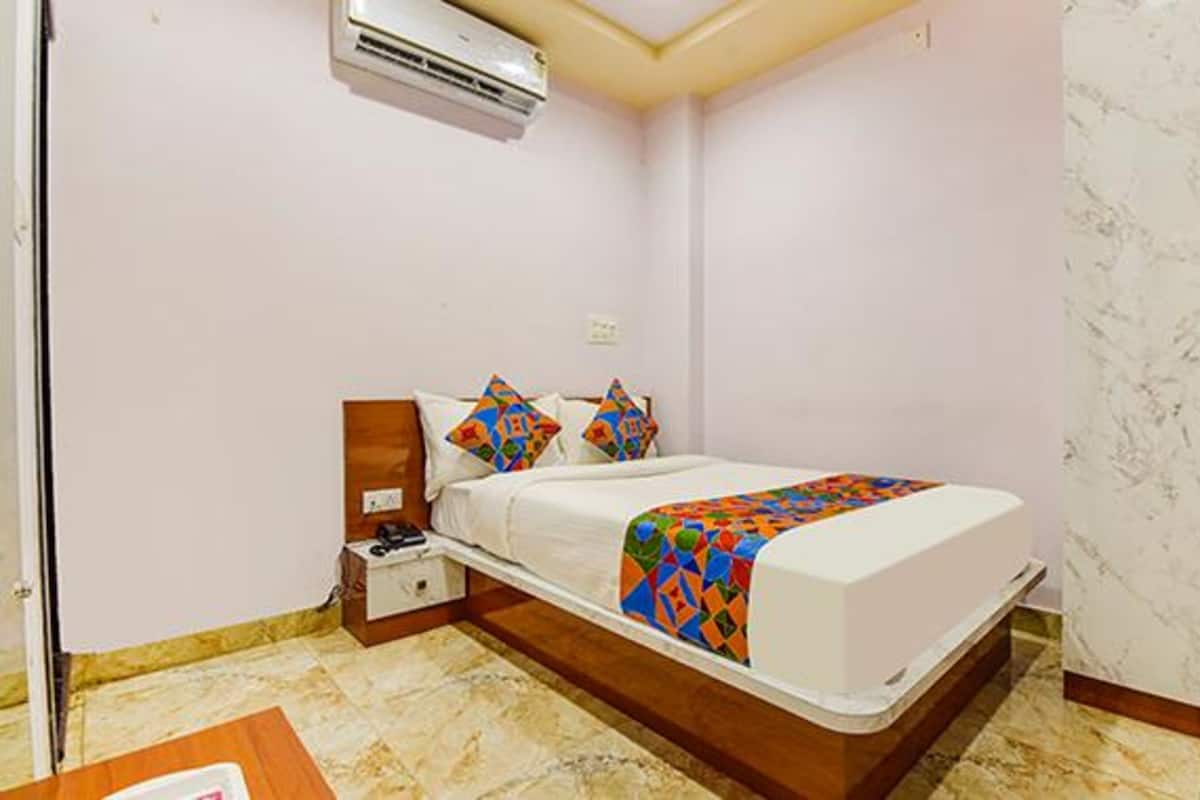 A bedroom with a bed, a nightstand, an air conditioner, and a wardrobe.