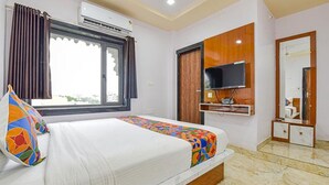 A hotel room with a bed, a television, a window with curtains, and a mirror. - Fabhotel Lali Palace (Udaipur)