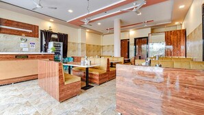A hotel lobby with a reception desk, seating areas, and a large mirror. - Fabhotel Lali Palace (Udaipur)