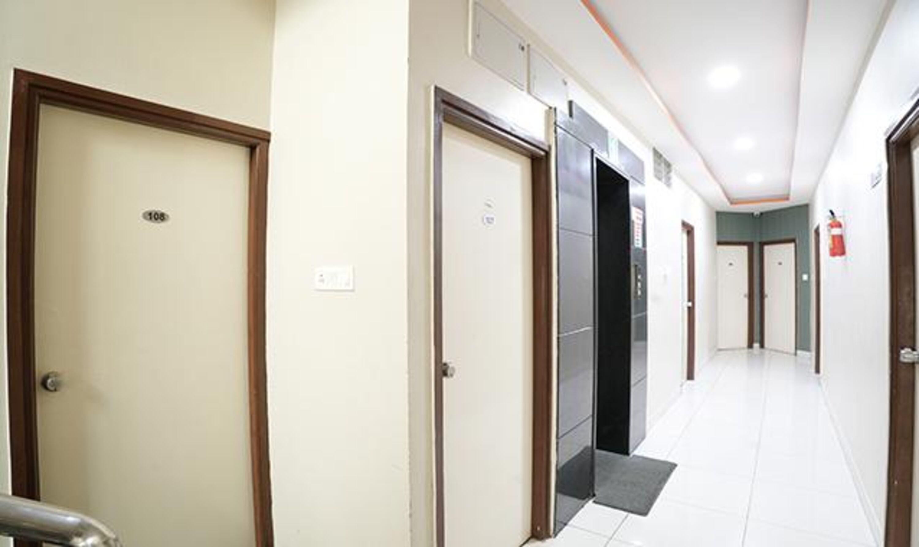 A hallway with doors, a fire extinguisher, and a tiled floor.