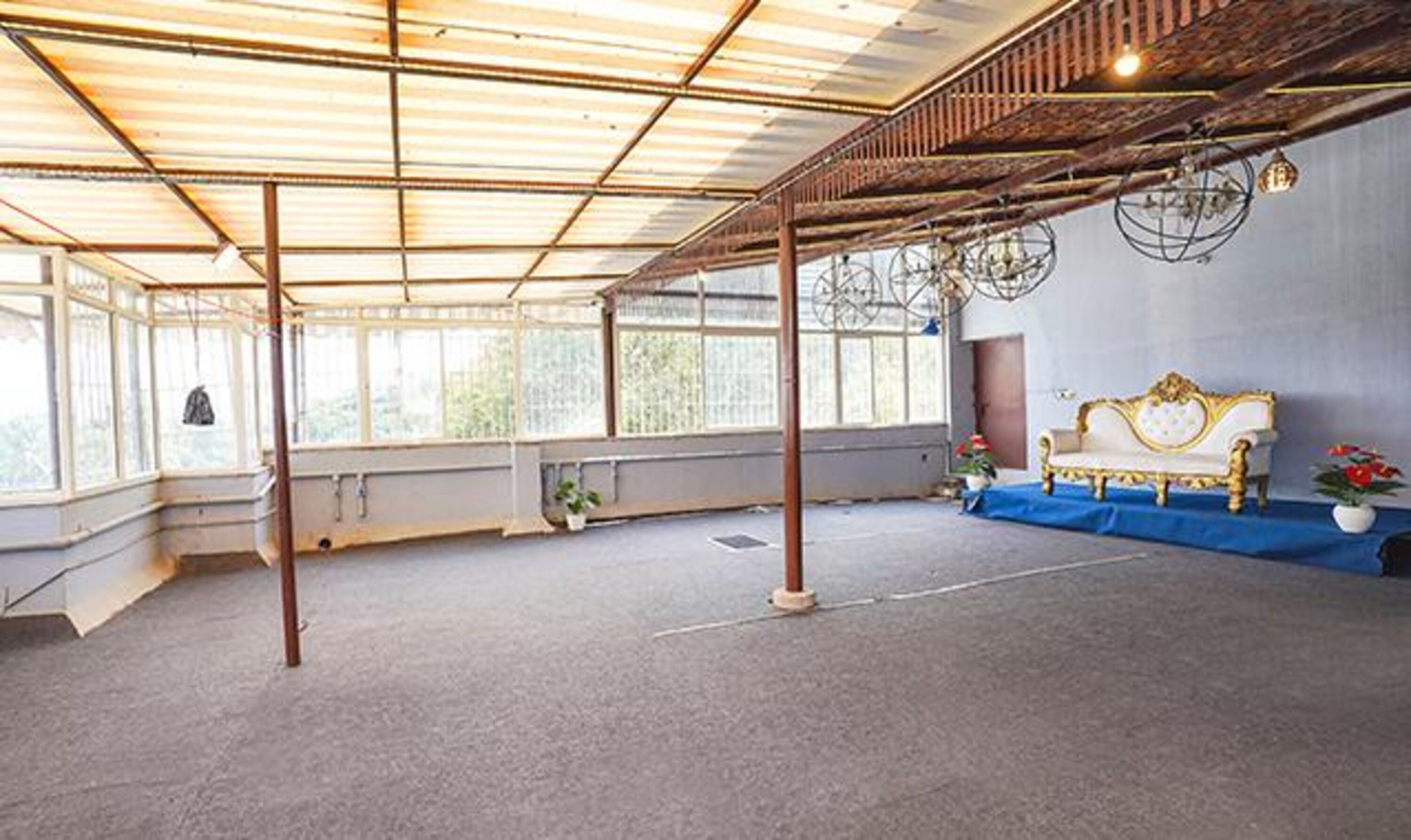 Una habitación amplia con techo alto, ventanas grandes y un banco decorativo.