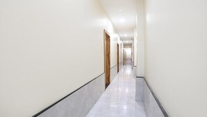 A long, narrow hallway with white walls and a tiled floor. - Fabhotel Radhika Ex (Chhatrapati Sambhajinagar)