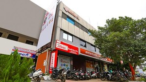 A multi-story building with a sign for 'Radhika Ex' and 'Radhika Ex Rooms'. There are several motorcycles parked in front. - Fabhotel Radhika Ex (Chhatrapati Sambhajinagar)