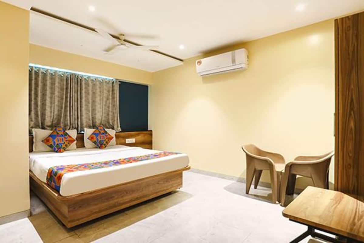 A modern hotel room with a bed, a desk, and a chair.