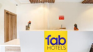 A reception desk with a 'fab hotels' sign, a small statue, and a red emergency exit sign. - Fabhotel Radhika Ex (Chhatrapati Sambhajinagar)