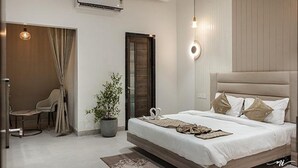 A modern bedroom with a large bed, a potted plant, a chair, and a door. - Fabhotel Prime Lavkush (Raipur)