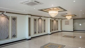 A spacious hotel corridor with ornate wall panels, a large chandelier, and a polished floor. - Fabhotel Prime Lavkush (Raipur)