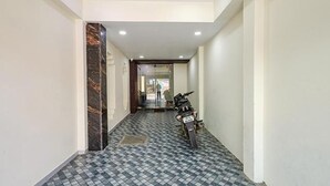 A hallway with a checkered floor, a marble column, and a parked motorcycle. - Fabhotel De Luxe (Chennai)