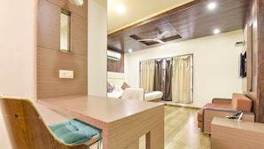 Une chambre d’hôtel moderne avec une table à manger en bois, un canapé, une télévision et un ventilateur de plafond.