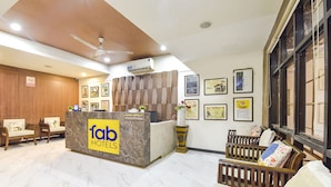 Un hall d’accueil d’hôtel avec un sol en marbre, des meubles en bois et un comptoir de réception portant l’inscription « fab hotels ».