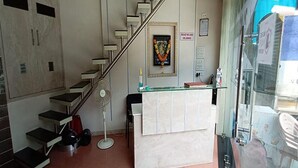 Un mostrador de recepción con superficie de vidrio, una obra de arte enmarcada encima y una escalera a la izquierda.