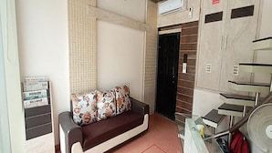 Una habitación con sofá, una mesita, un ventilador y una escalera.