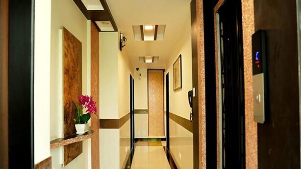 Un pasillo de hotel con mostrador de recepción, un teléfono en la pared y un ascensor.