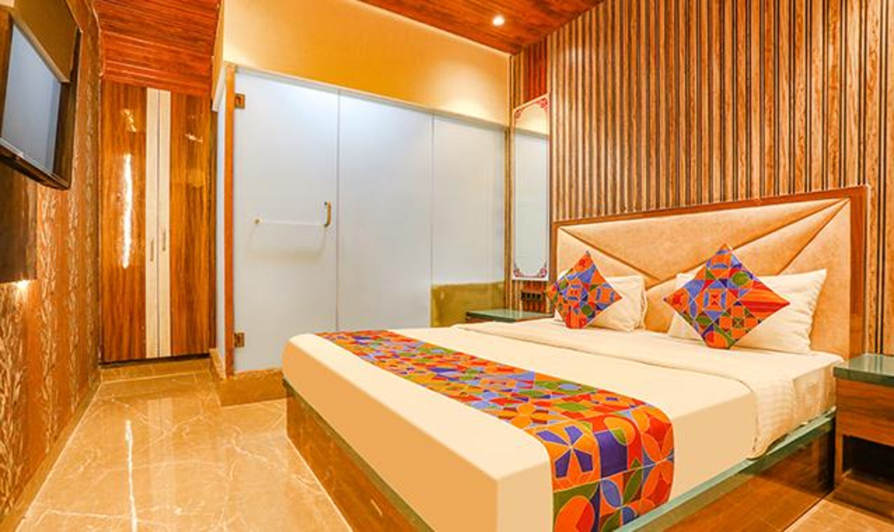 A bedroom with a bed, a wardrobe, and a television mounted on the wall.