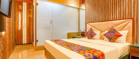 A bedroom with a bed, a wardrobe, and a television mounted on the wall.