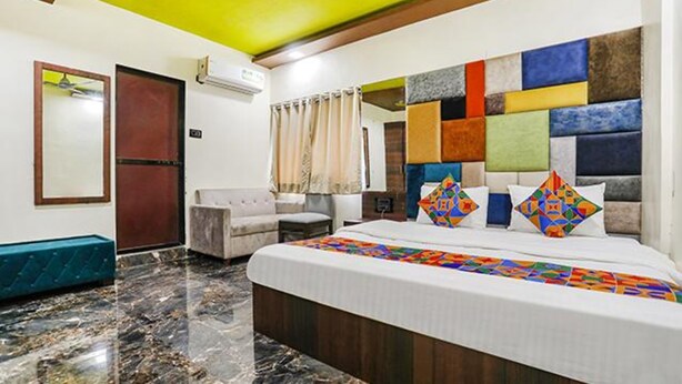 Una habitación de hotel con cama, sofá, espejo y ventana con cortinas.