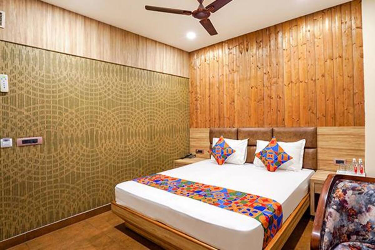 A hotel room with a wooden headboard, a bed with a colorful quilt, and a ceiling fan.