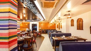 A restaurant with booths and tables, wooden walls, and a striped wall decoration. - FabHotel Prime Tushar Elegant (Ghaziabad)