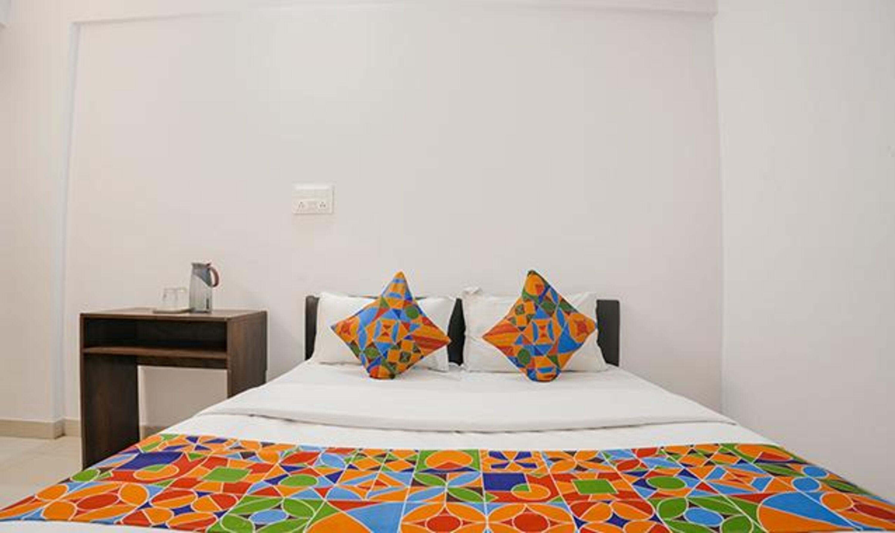 Une chambre à coucher avec un lit, deux oreillers, une table de chevet et une machine à café.