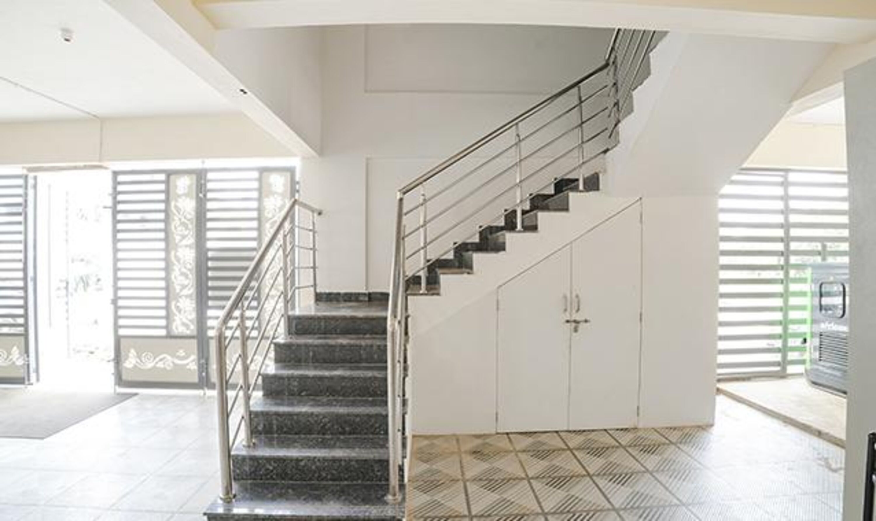 A staircase with metal railings leading to a landing with cabinets.