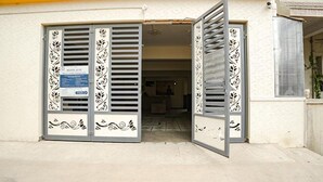 Η είσοδος ενός ξενοδοχείου με διακοσμητικά μεταλλικά παντζούρια και μια επιγραφή.