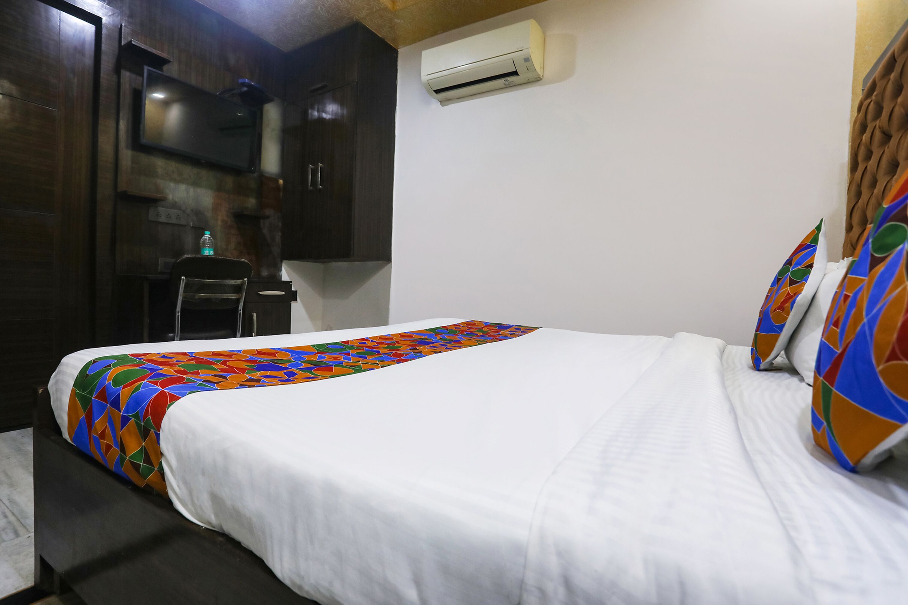 Una habitación de hotel con cama, escritorio y aire acondicionado.