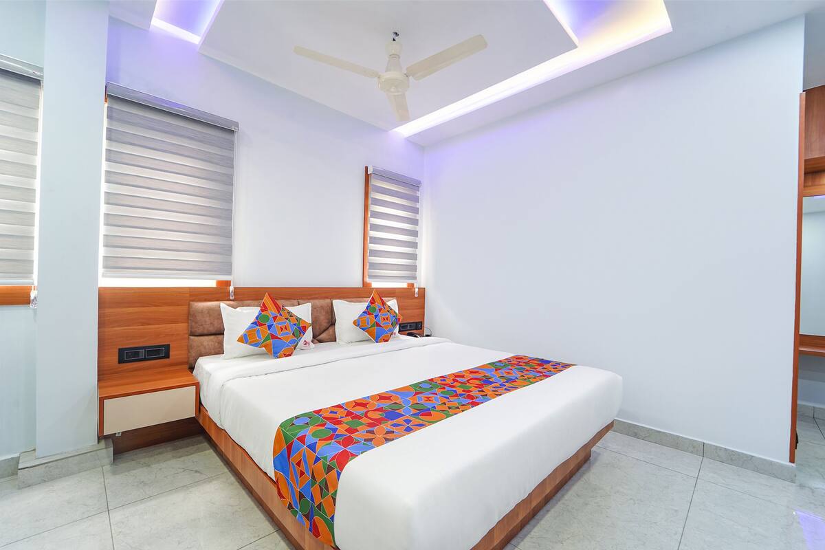 A modern hotel room with a large bed, wooden headboard, and a ceiling fan.